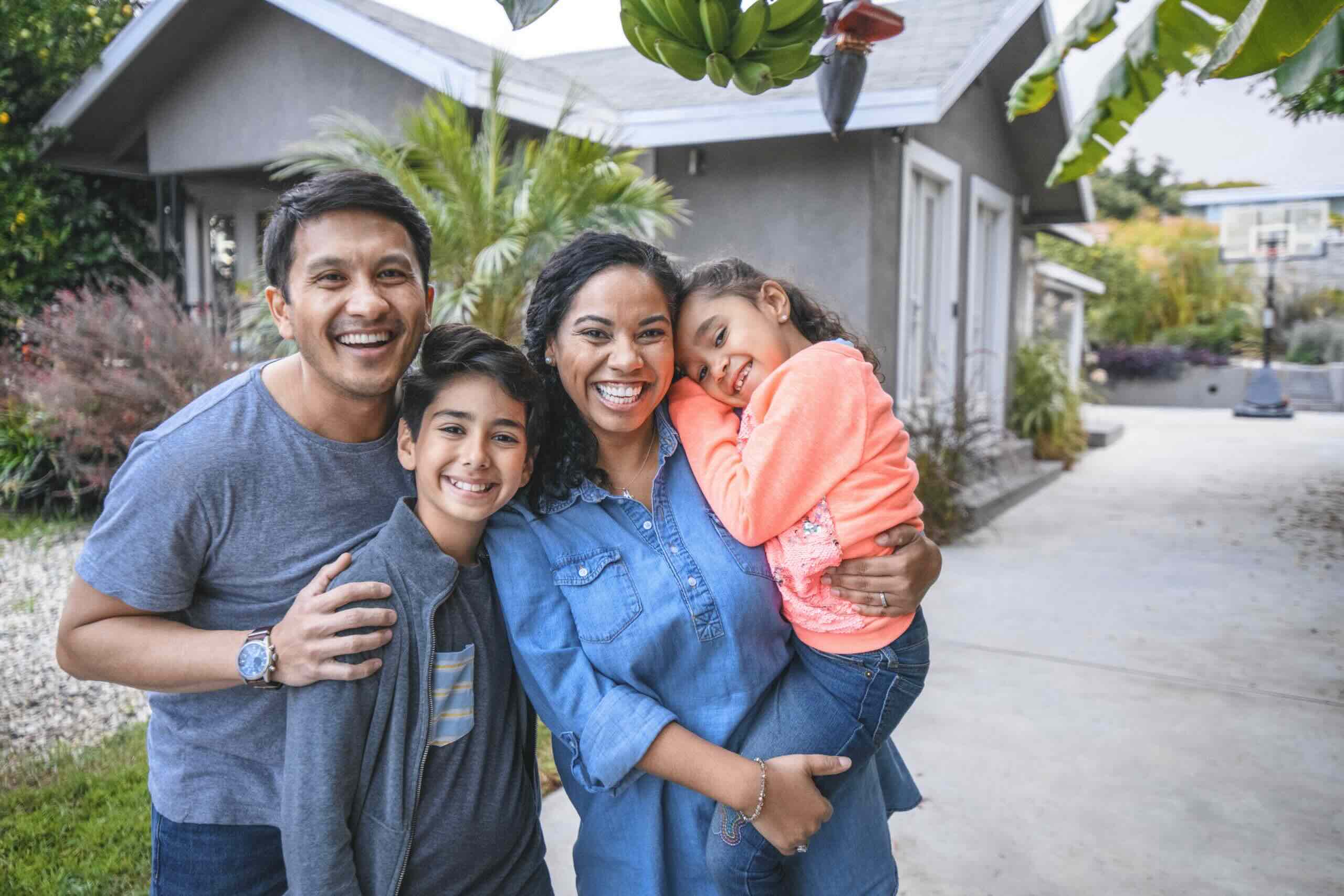 A smiling and happy young family in front of their new home.